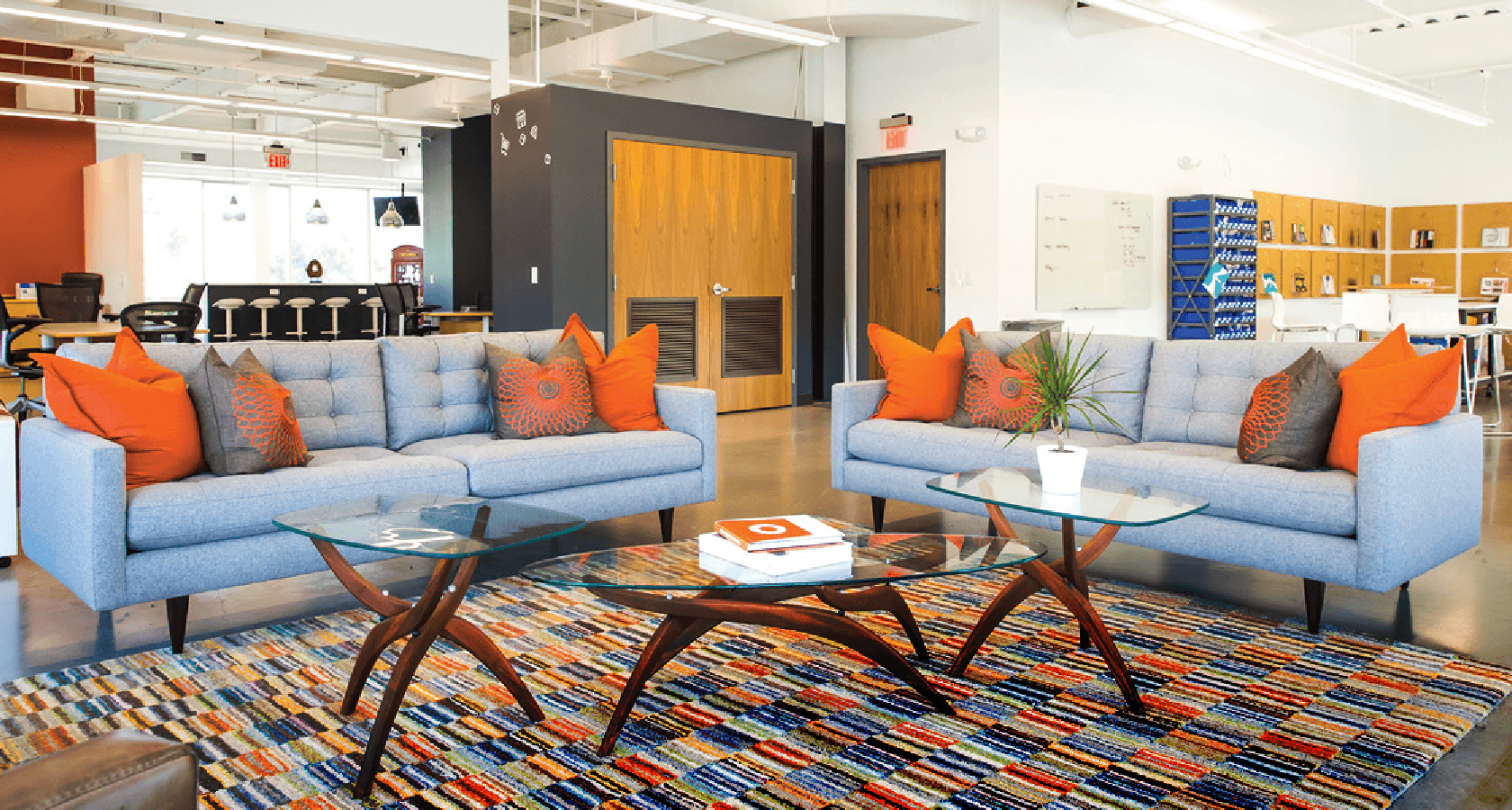 two grey couches with orange accessories in an office common area
