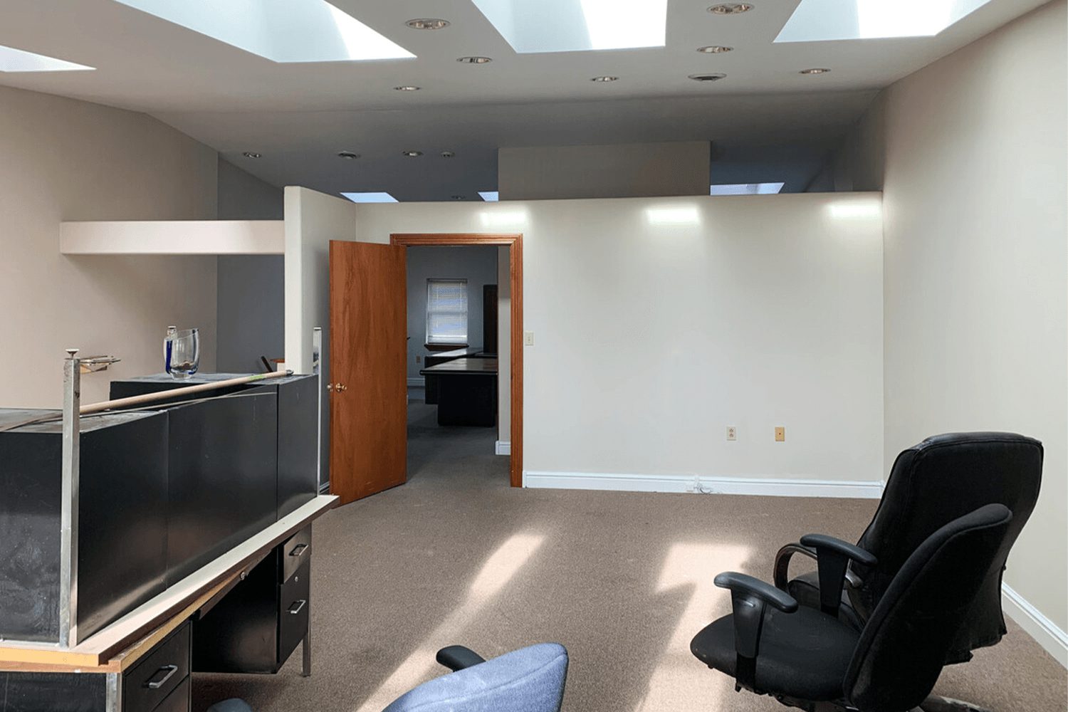 office psace with desks and a high ceiling with skylights