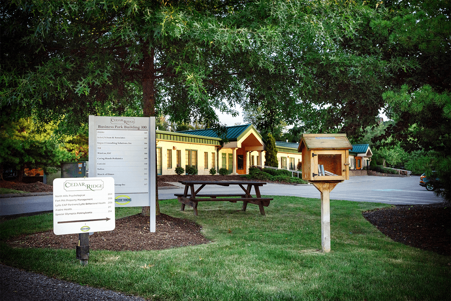 grass area in front of office building with signs and a picnic table