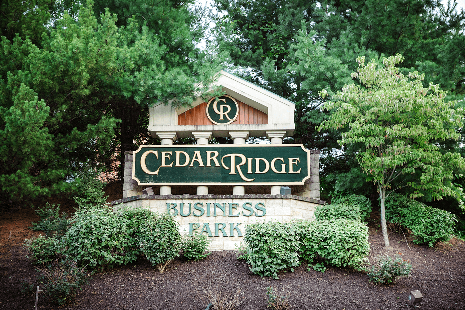 Cedar Ridge Business Park monument sign surrounded by bushes and trees