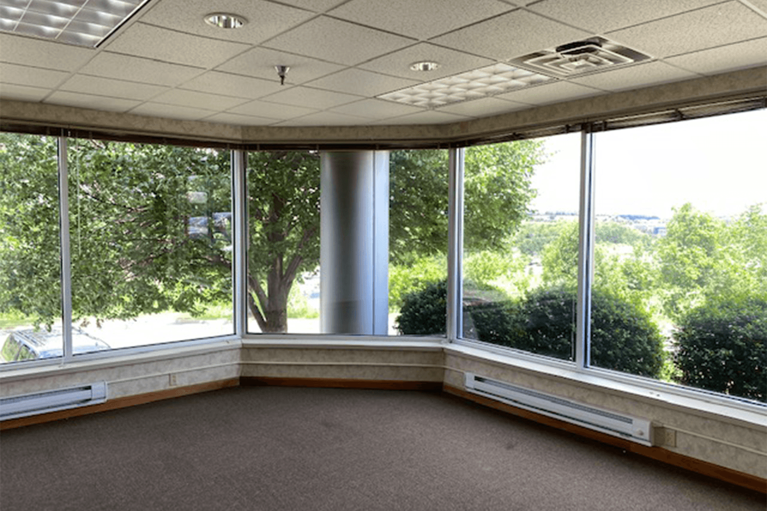 empty room with large windows that look out into trees and bushes
