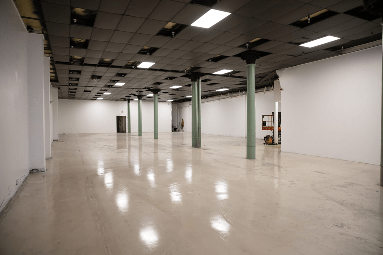 empty room with high ceilings, white walls, and green pillars