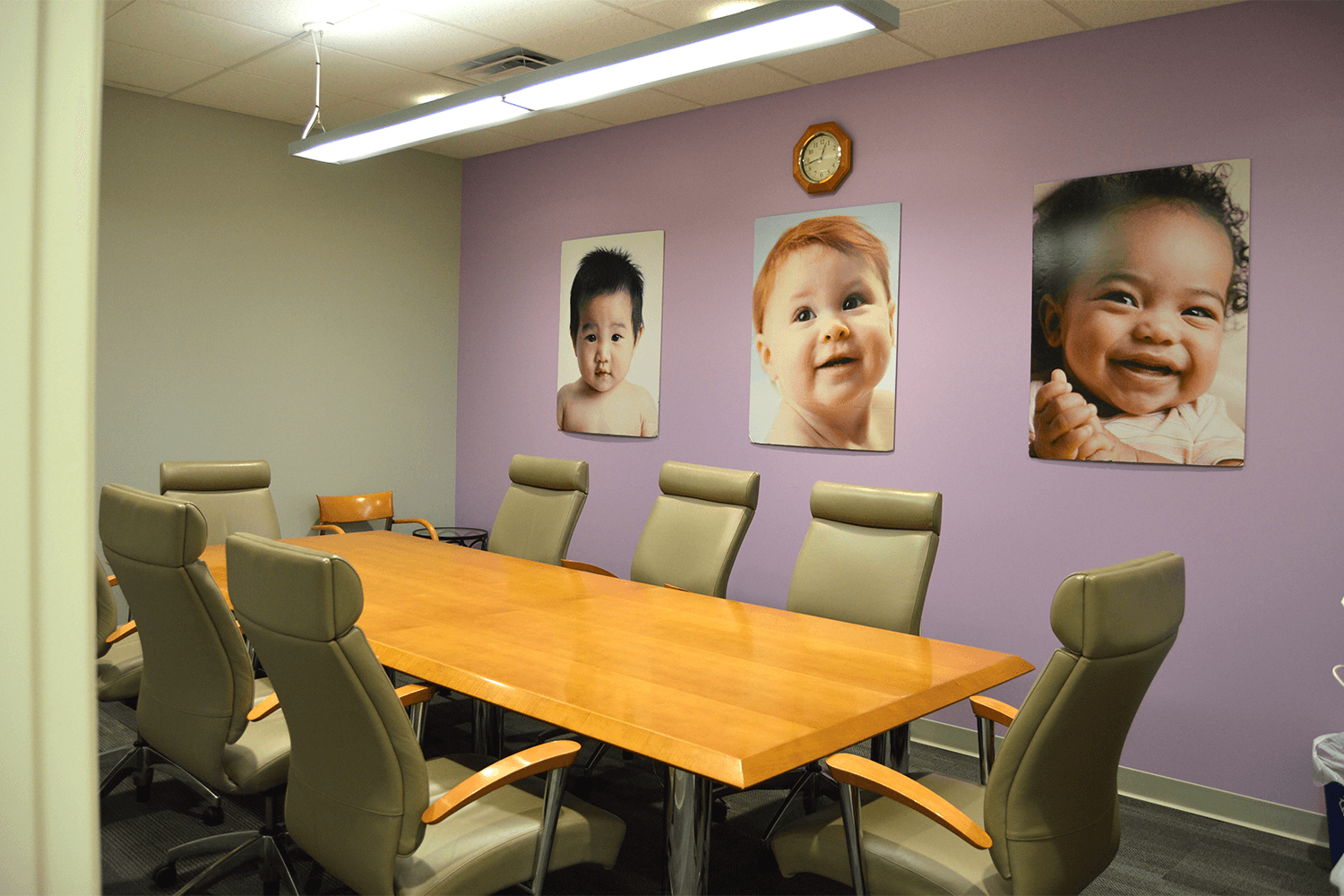 conference room with a table and chairs, and a purple accent wall with photos hanging on it