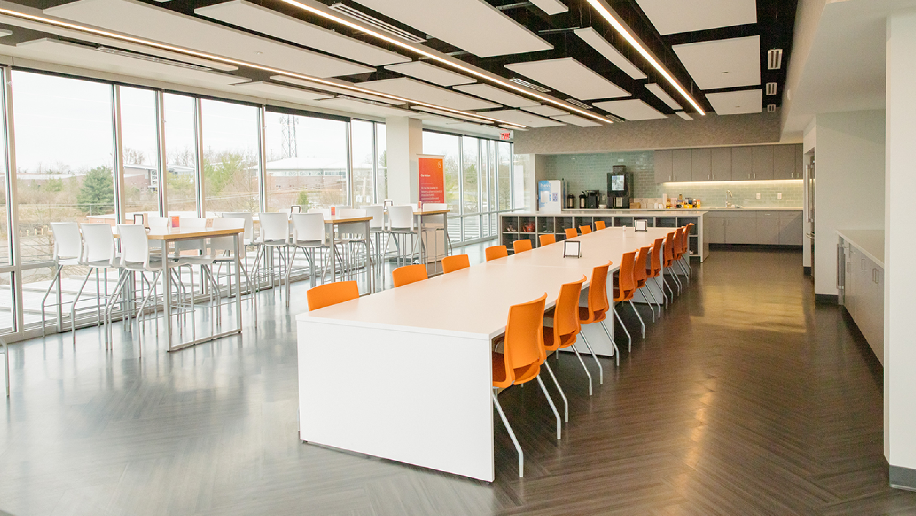 Café inside of Beacon I with bright orange chairs, a white table, and floor-to-ceiling windows