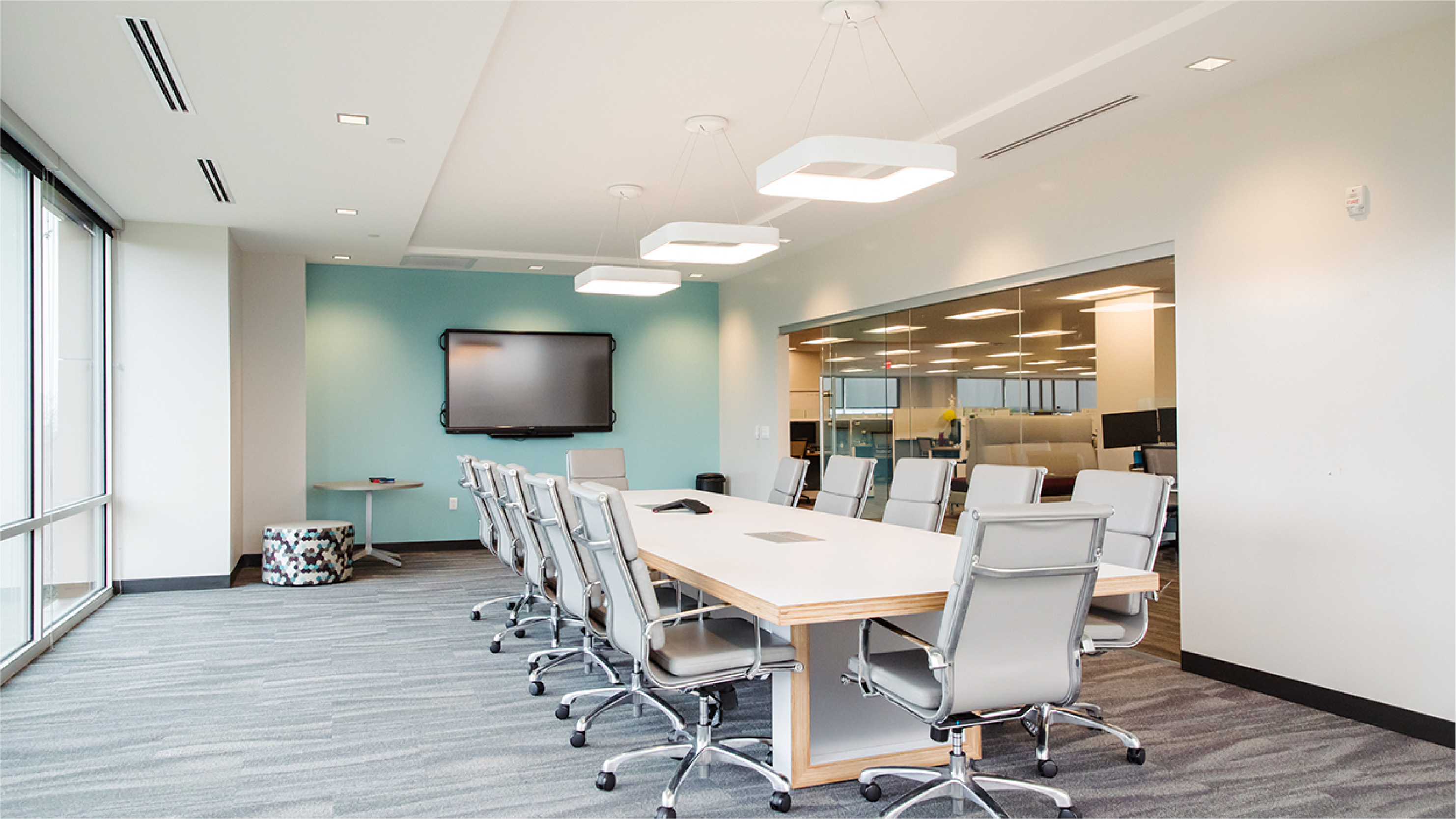 Conference room with modern light fixtures, gray chairs, white walls and a turquoise accent wall