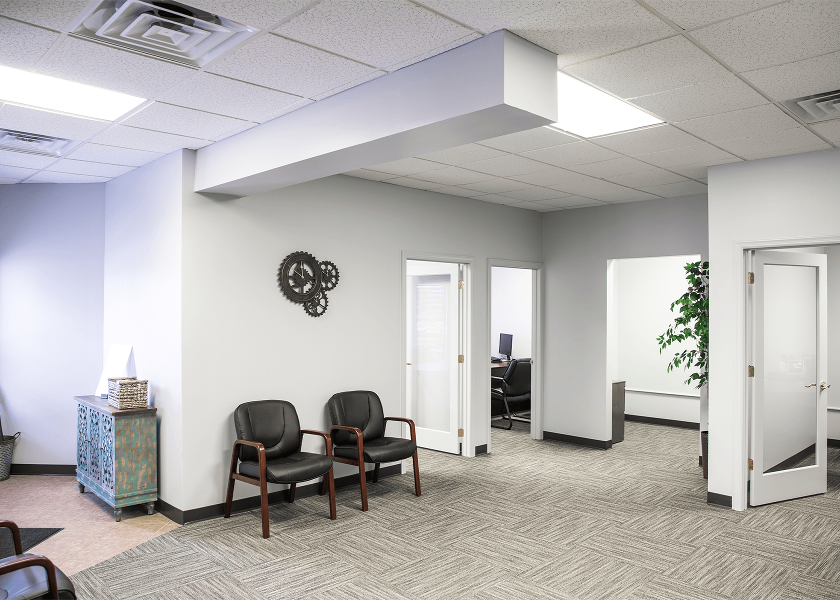 Office suite with bright white walls, light gray carpet, and waiting chairs
