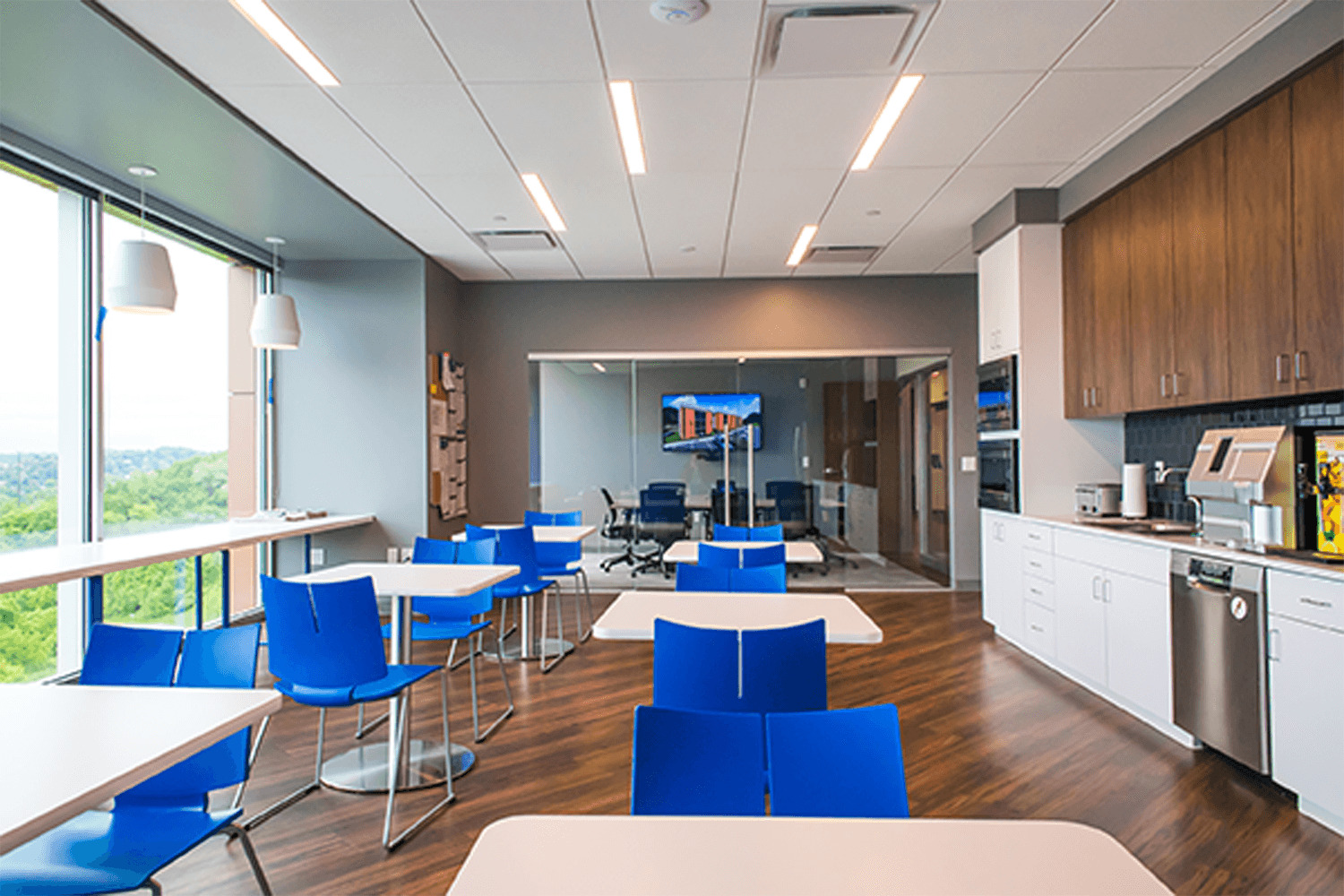 café/break area with kitchen appliances, white tables, and vibrant blue chairs