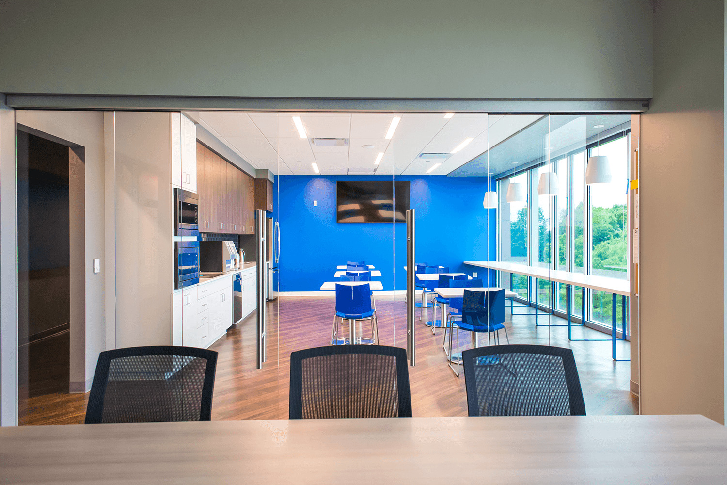 view from conference room into a café/break area with a vibrant blue accent wall
