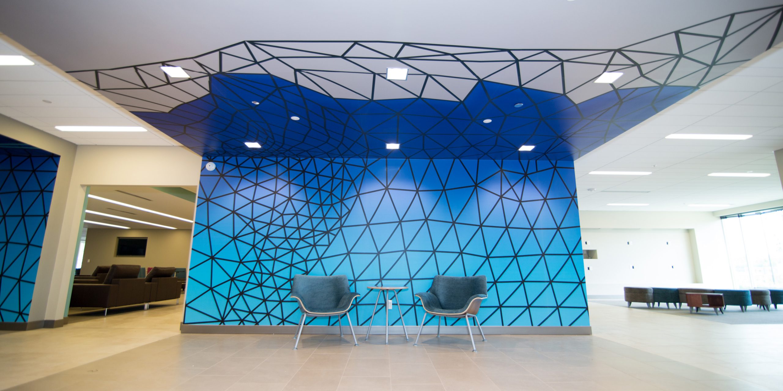 two chairs in a lobby with a geometric vinyl wall wrap
