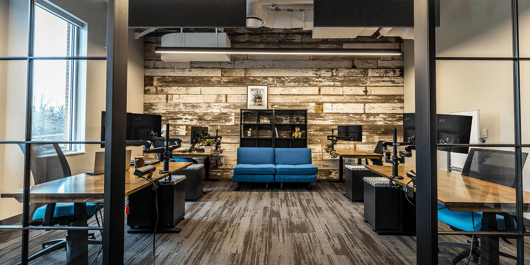 office with desks and computers and a rustic wood accent wall