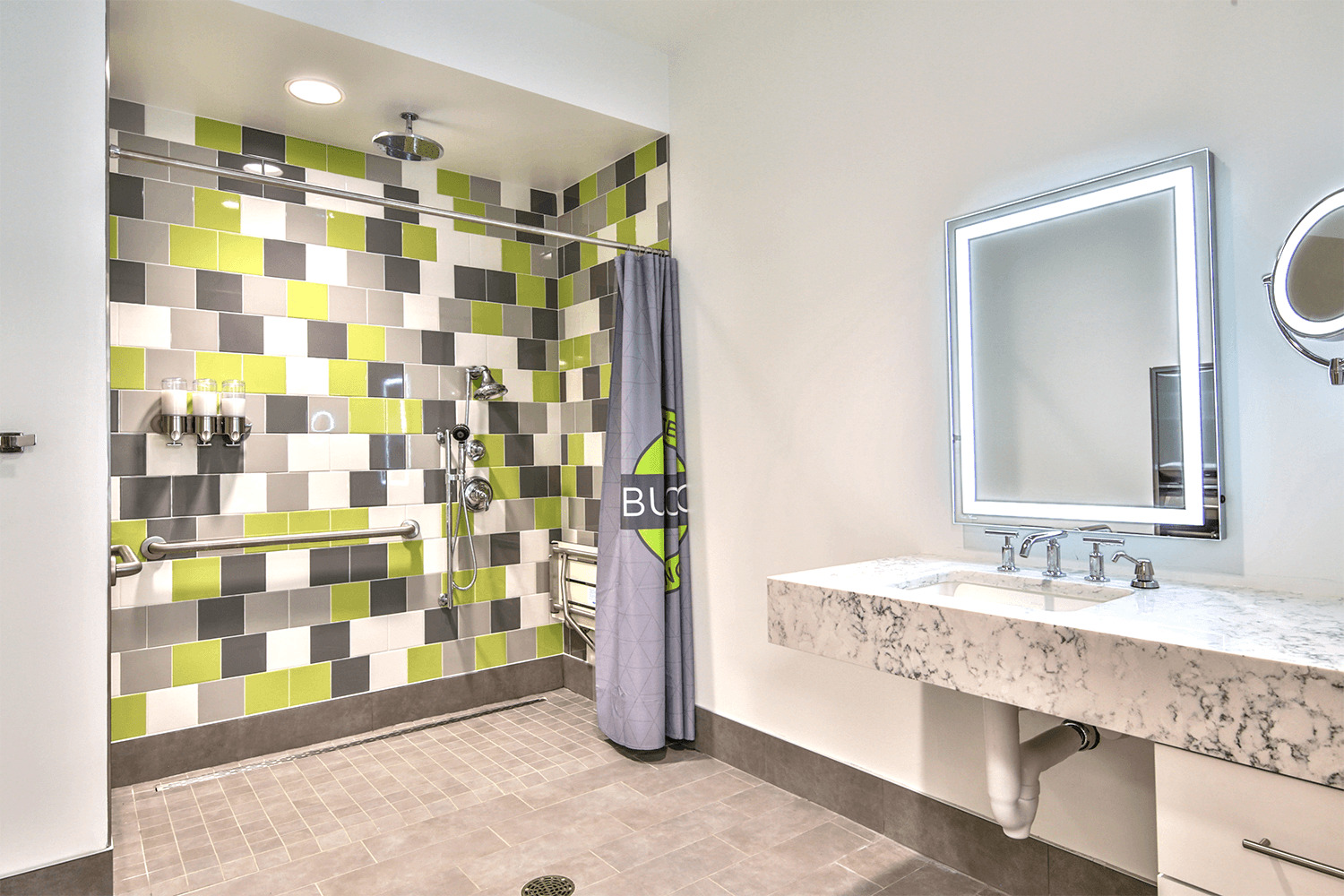 restroom with a large tile shower and a mirror with built-in lighting