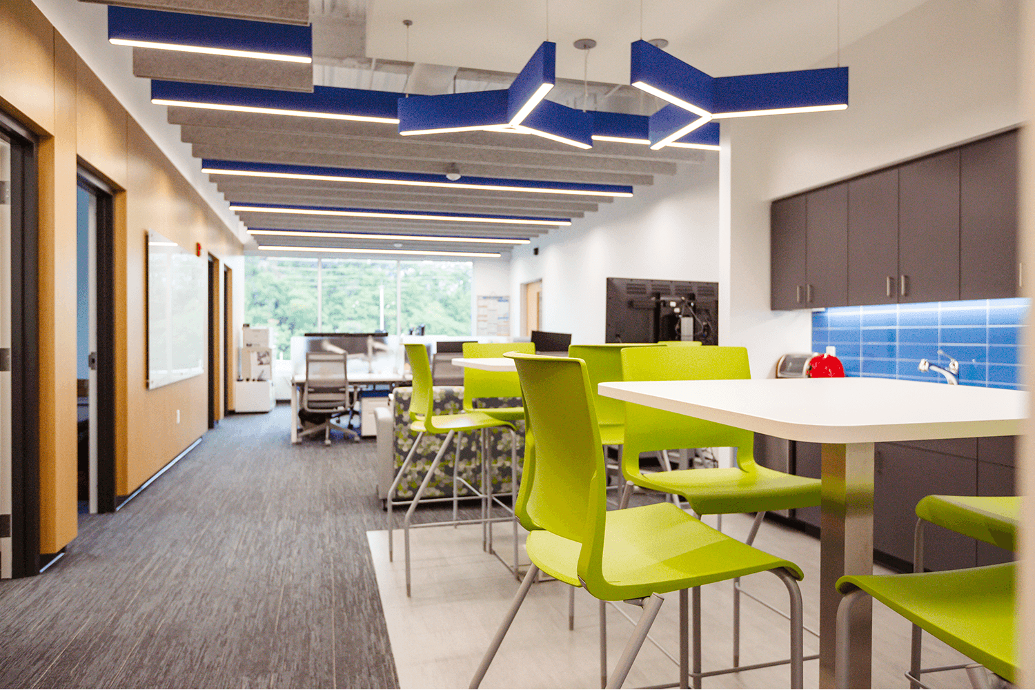break area with lime green chairs, white tables, and geometric light fixtures
