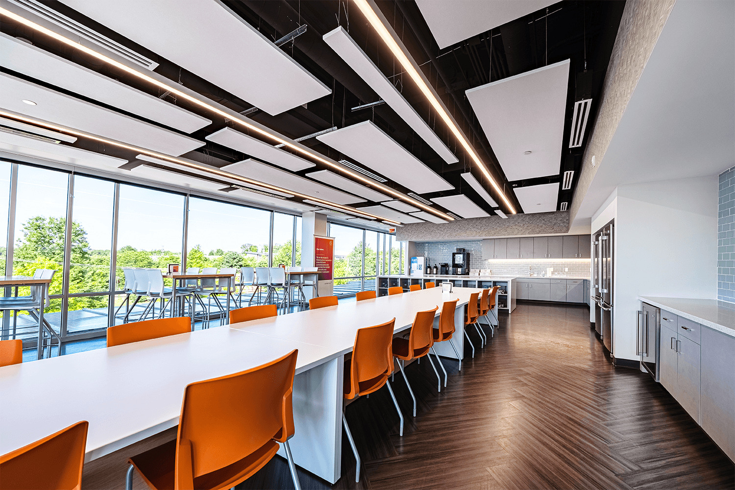 large café/break area with white tables and vibrant orange chairs