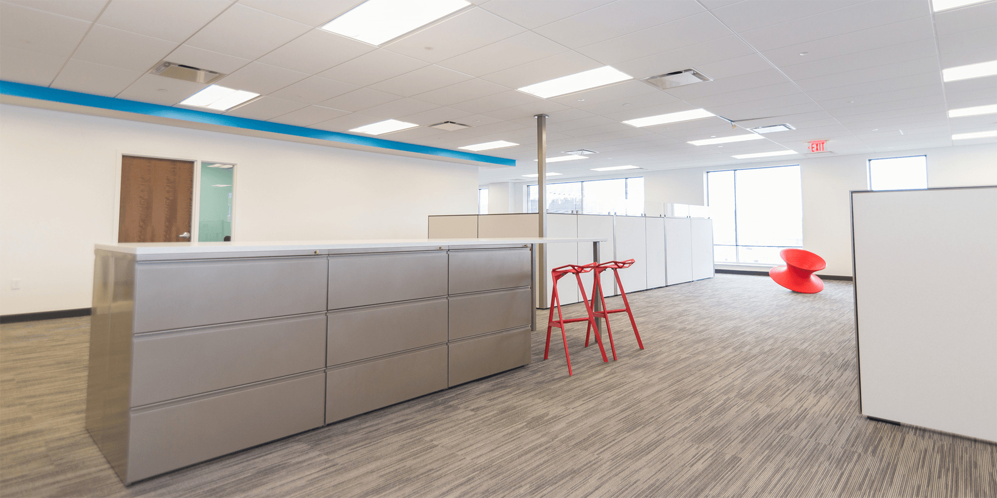 large open office area with storage drawers, cubicles, and a spinning axis chair