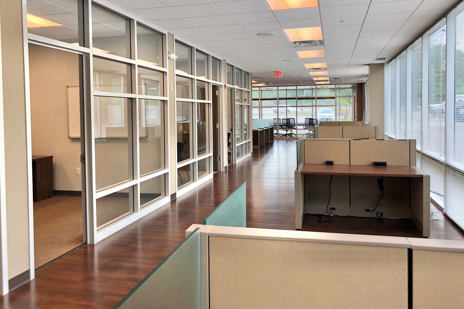 Hallway with private offices on left and desk cubicles to right
