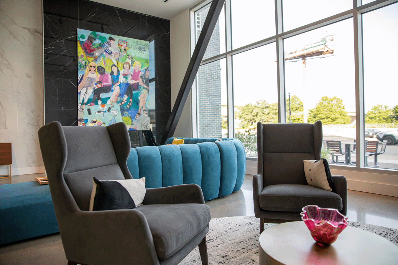 two chairs seated around a table in a lobby with a colorful painting