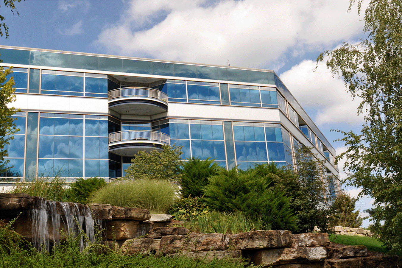 glass building overlooking a waterfall surrounded by greenery