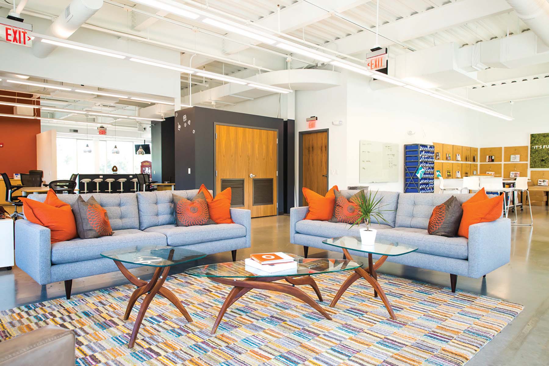 Collaborative workspace with two blue couches and orange accent pillows