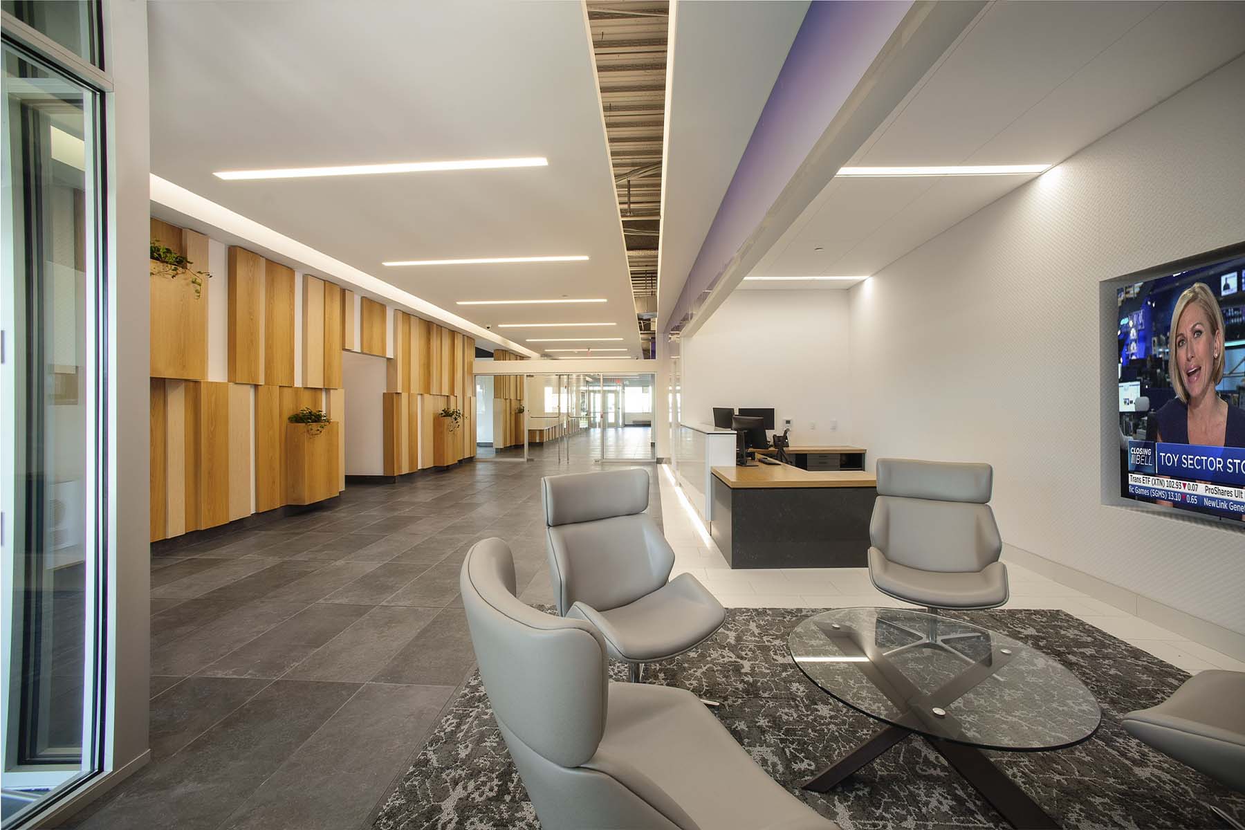 Entrance and lobby area with modern gray chairs, and walls with wood finishes