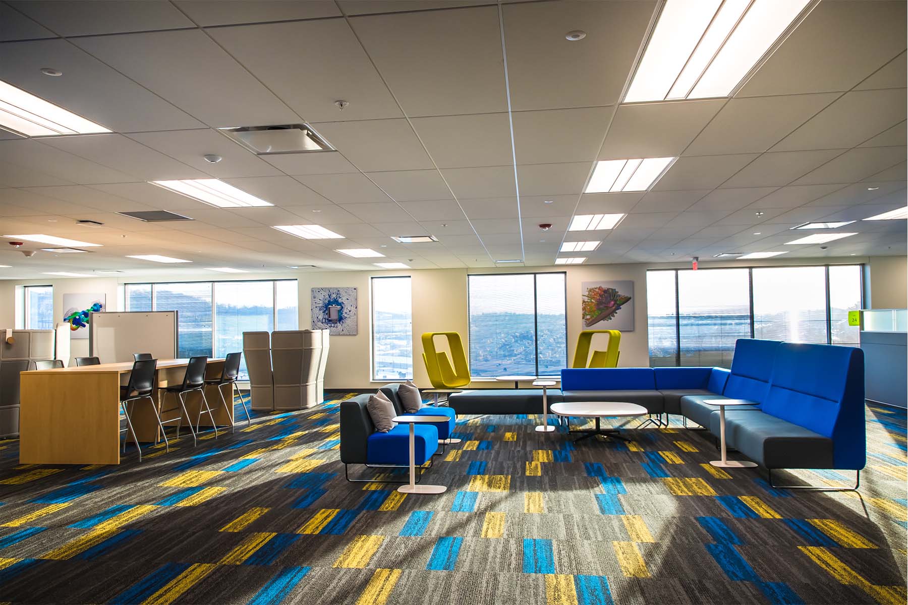 Office with blue, yellow, and gray furniture, and carpet, and large windows