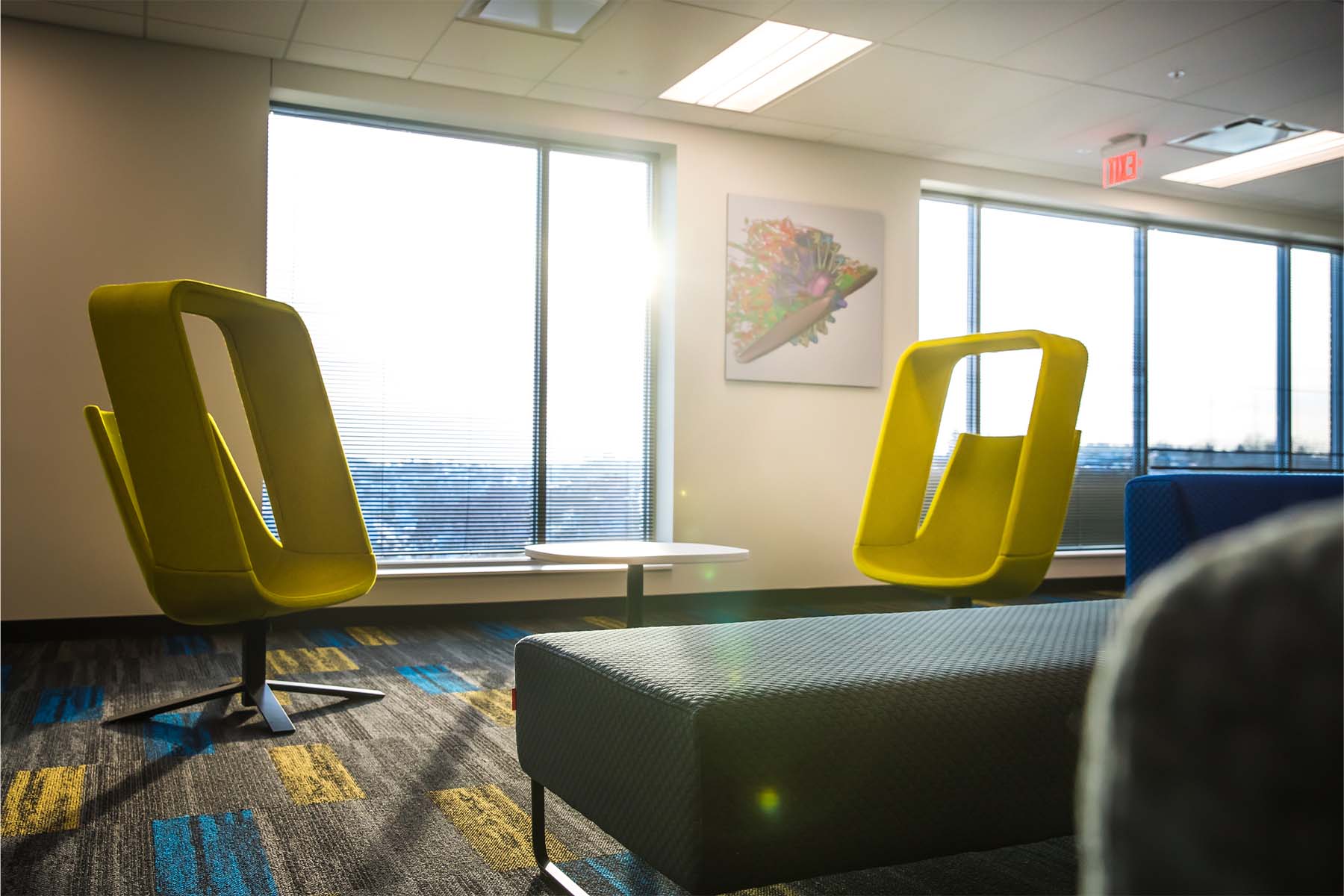 Two bright yellow chairs sitting in front of a wall of with large windows
