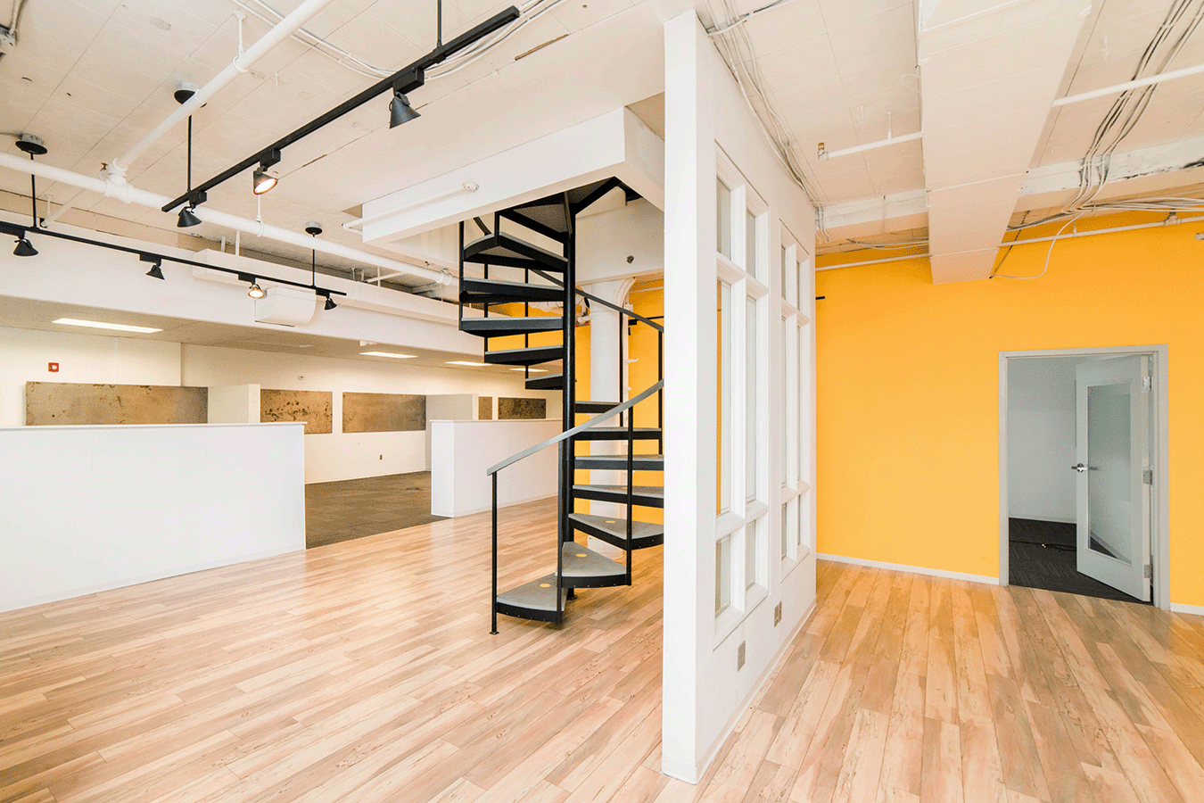 large room divided by windows with a spiral staircase going upstairs
